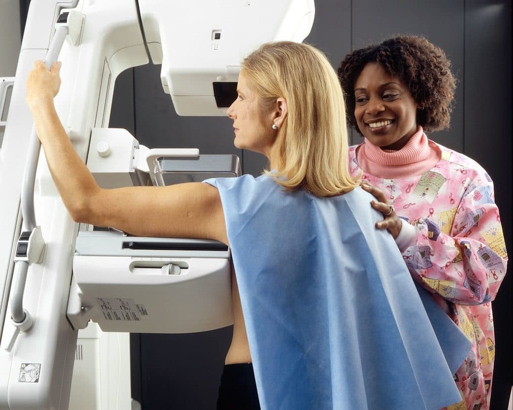 A radiographer positioning a patient at a mammography machine