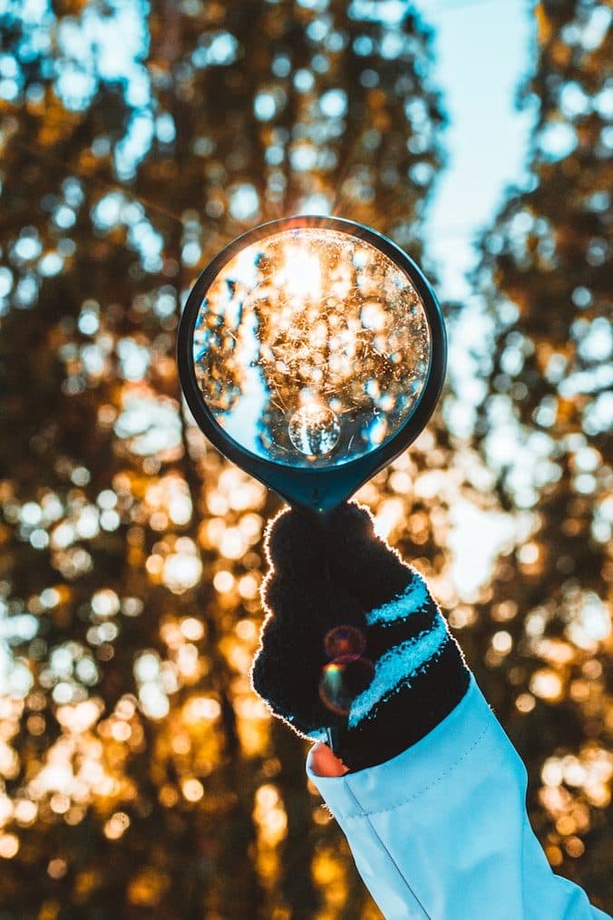 A hand holding a glass sphere that gathers the light behind it