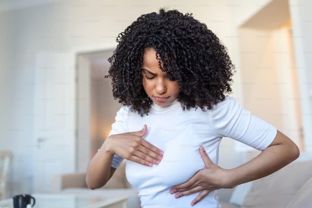 A woman performing a breast self-examination at home